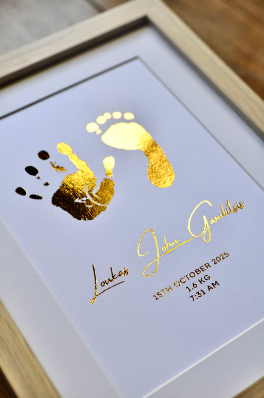 Framed artwork with gold foil baby footprints and baby's name on a white background