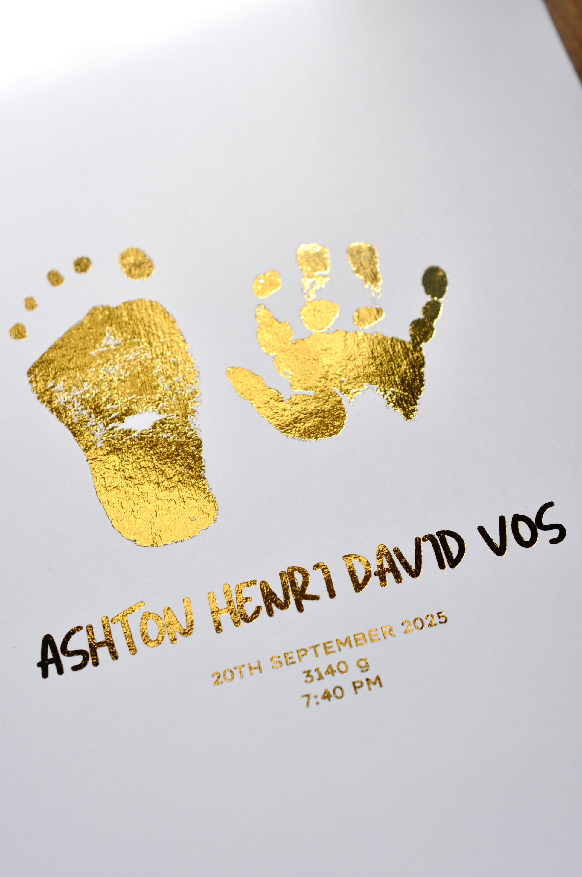 Gold foil hand and footprints with baby's name and birth details on a white background