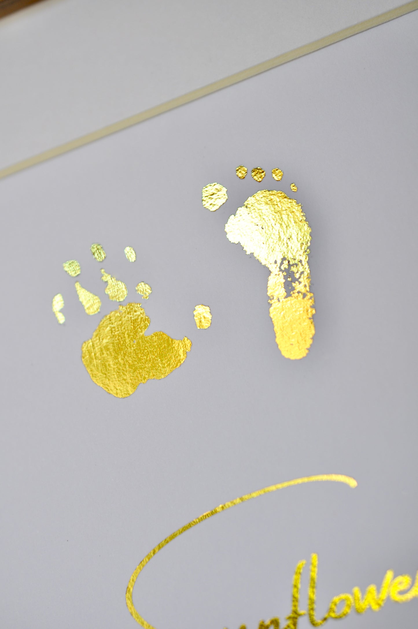 Gold footprints and handprints on a white background with name and birth details