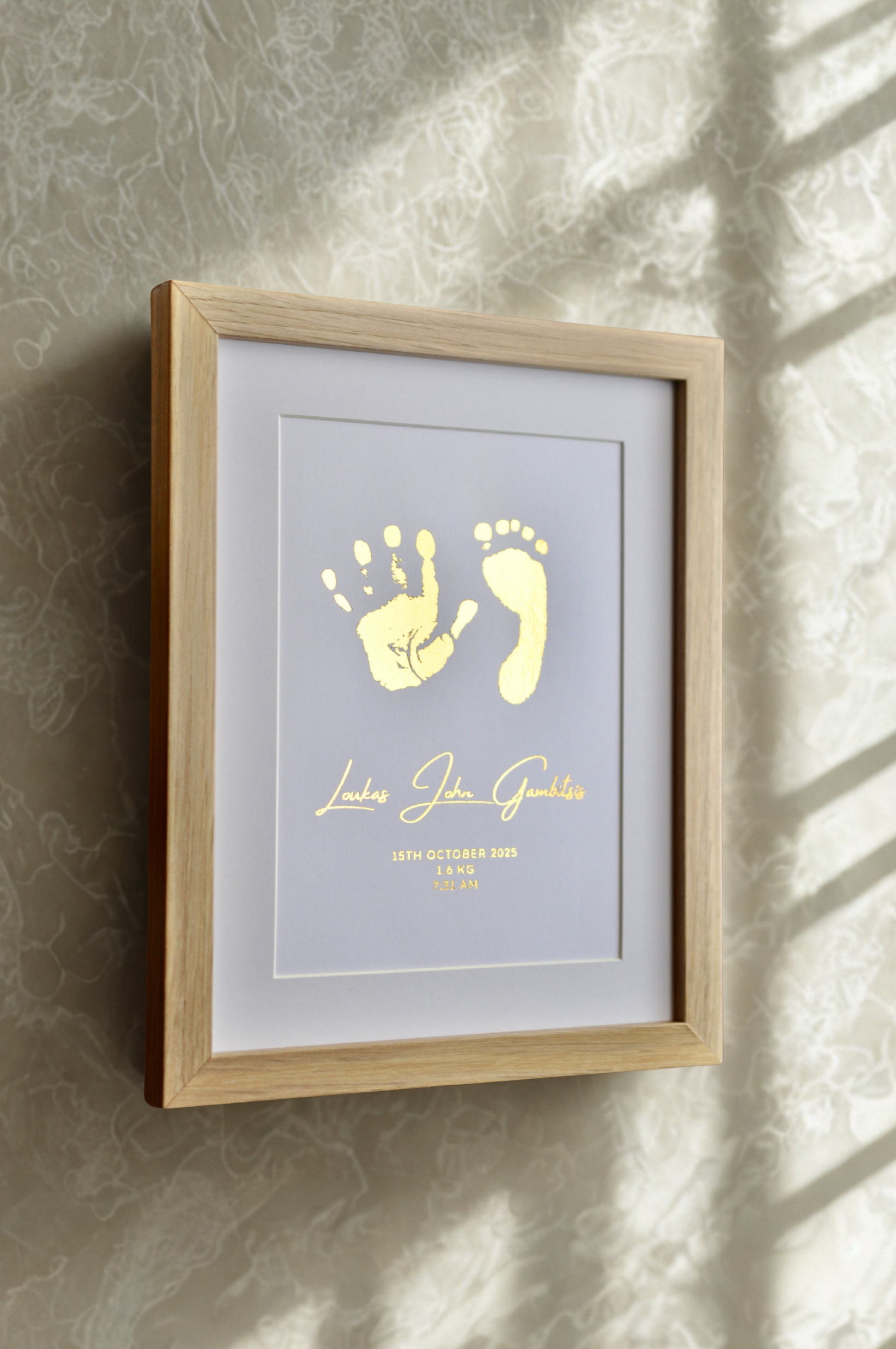 Framed artwork with baby hand and footprints on a textured wall