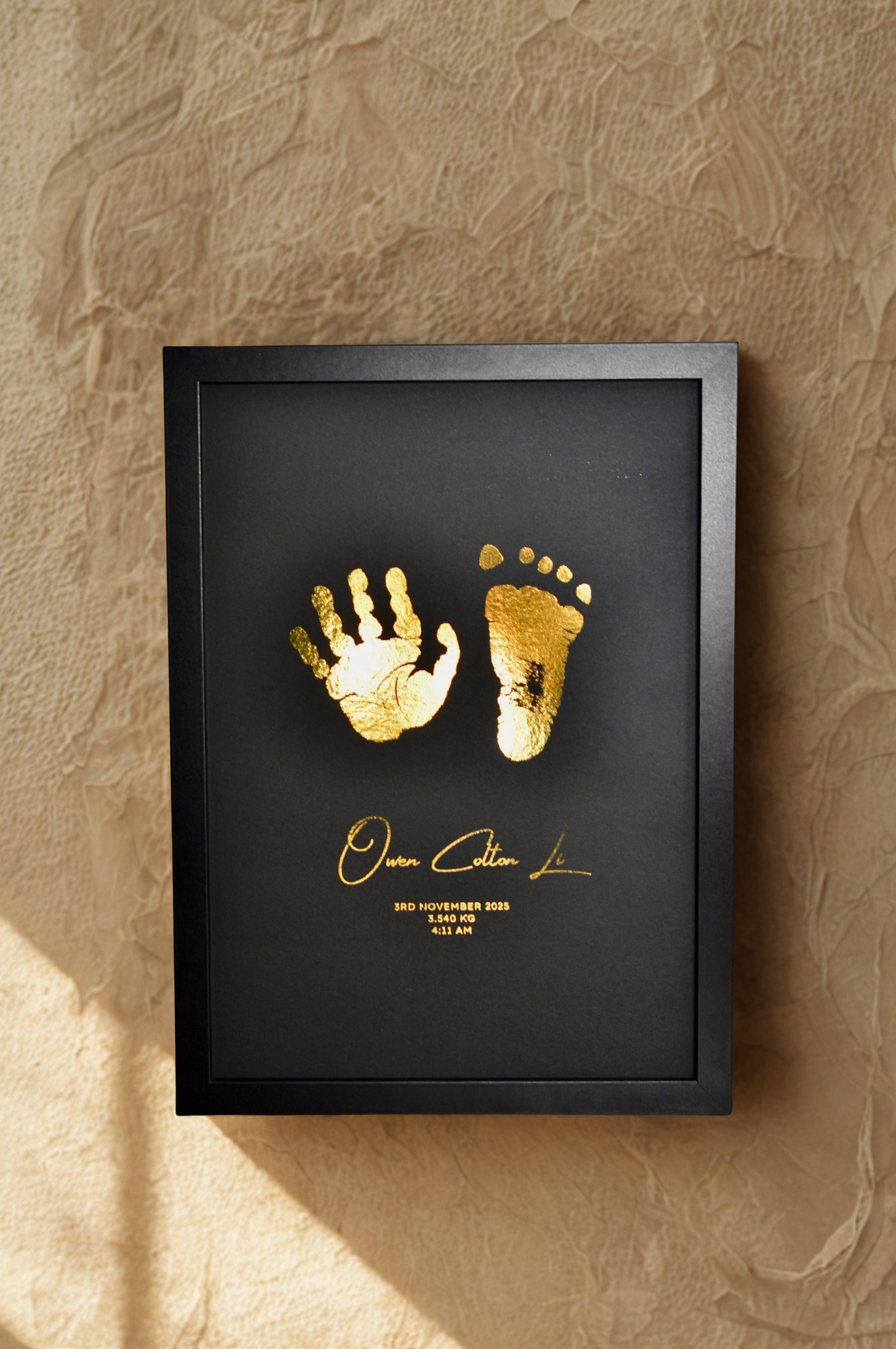Framed gold hand and footprints on a textured wall