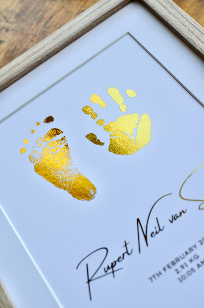 Framed artwork with gold handprints and signature on a white background