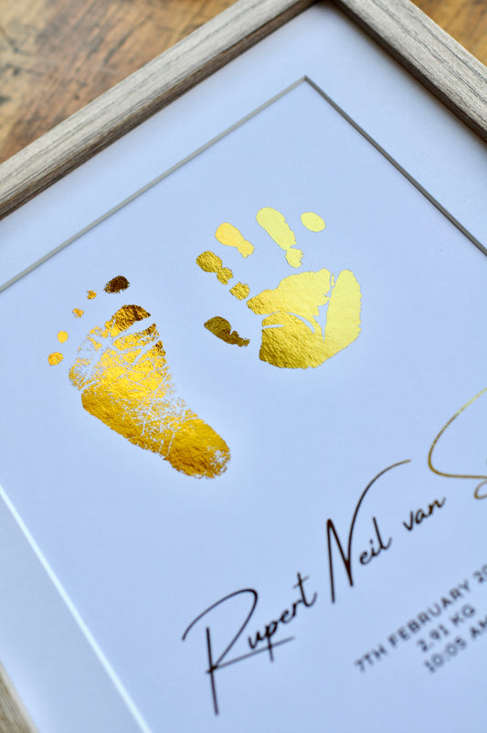 Framed artwork with gold handprints and signature on a white background