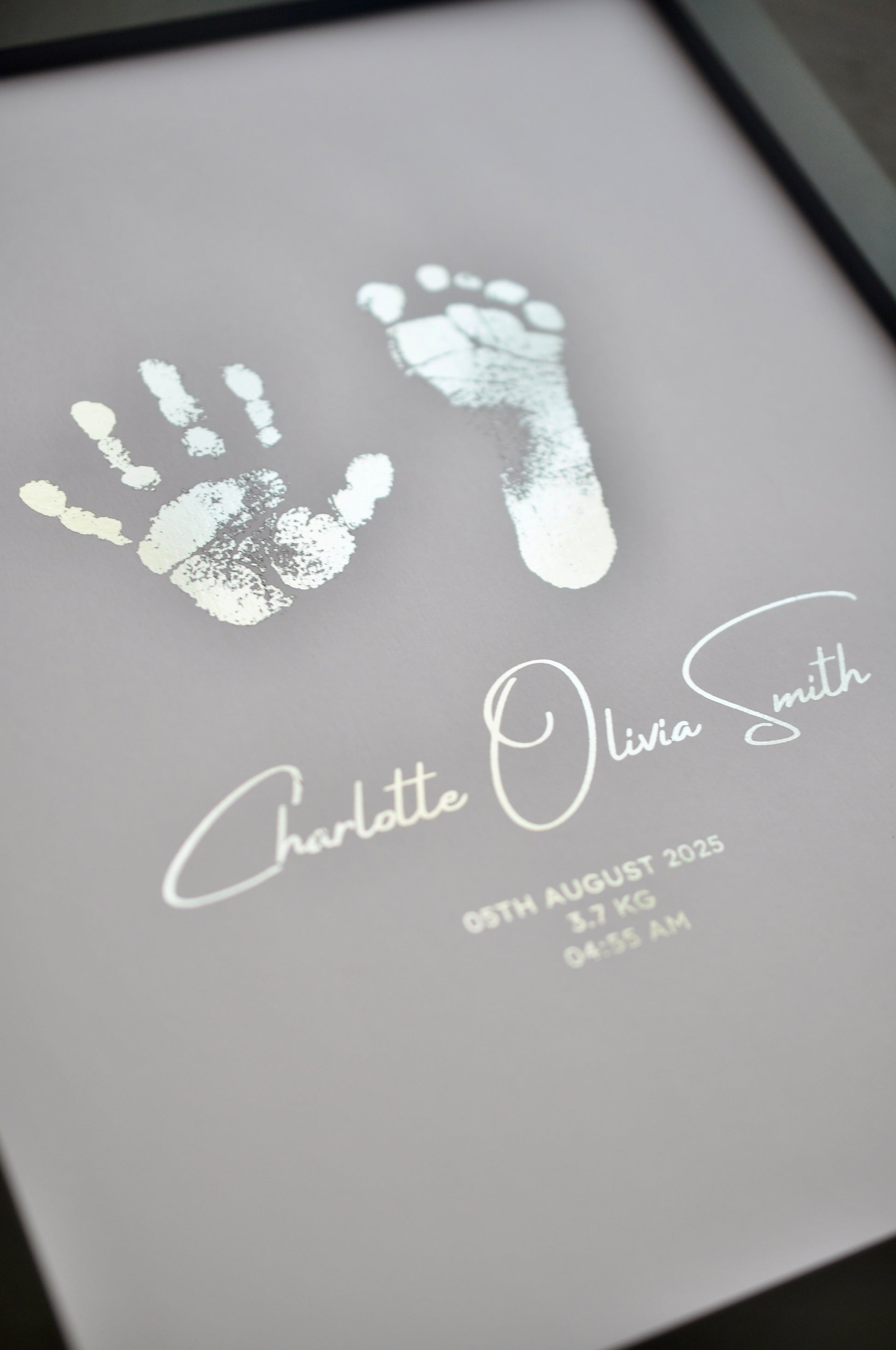 Hand and footprints with a name and date on a white background
