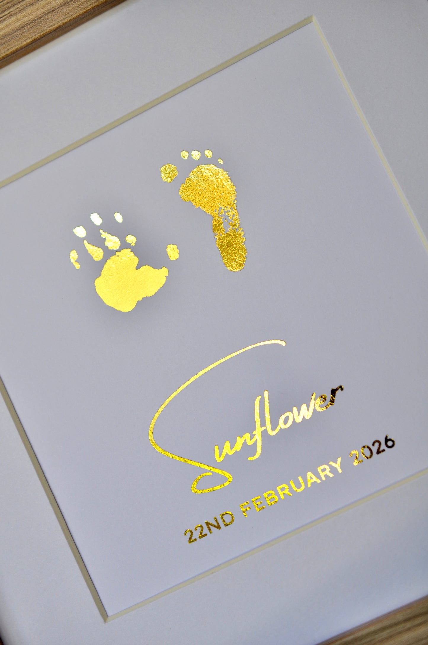 Framed paper with gold footprints and 'Sunflower' text on white background