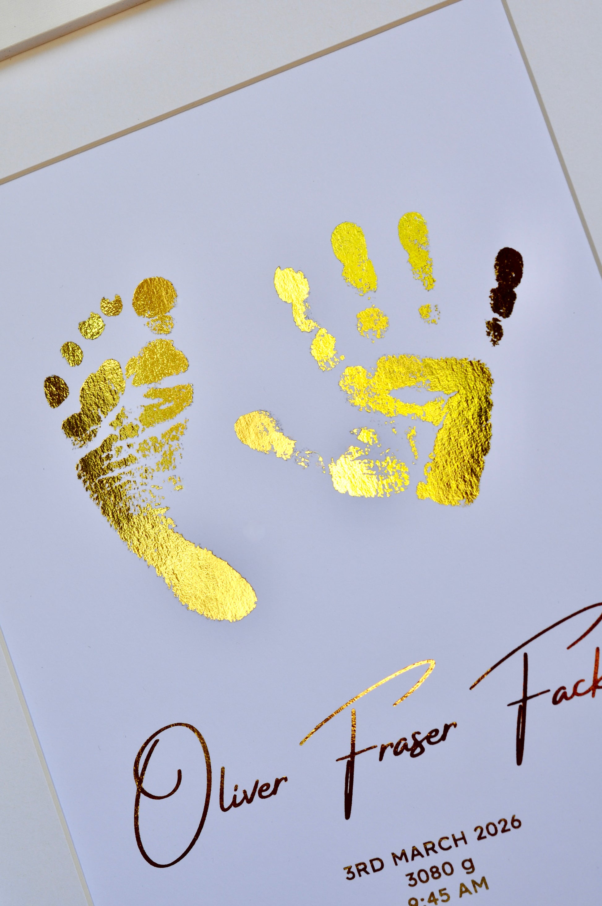Gold foil hand and footprints on a white card with text