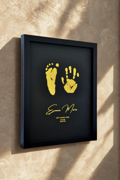 Framed artwork with gold hand and footprints on a textured wall.