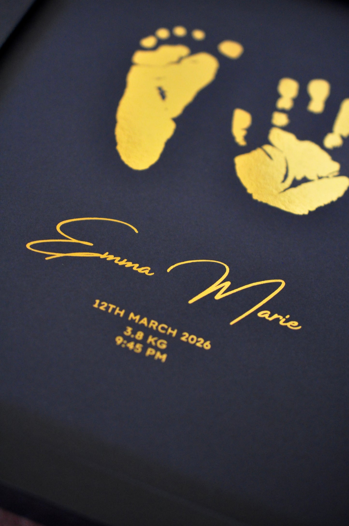 Black card with gold baby footprints and personalized text on a black background