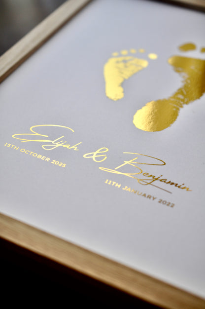 Framed print with gold footprints and names on a white background