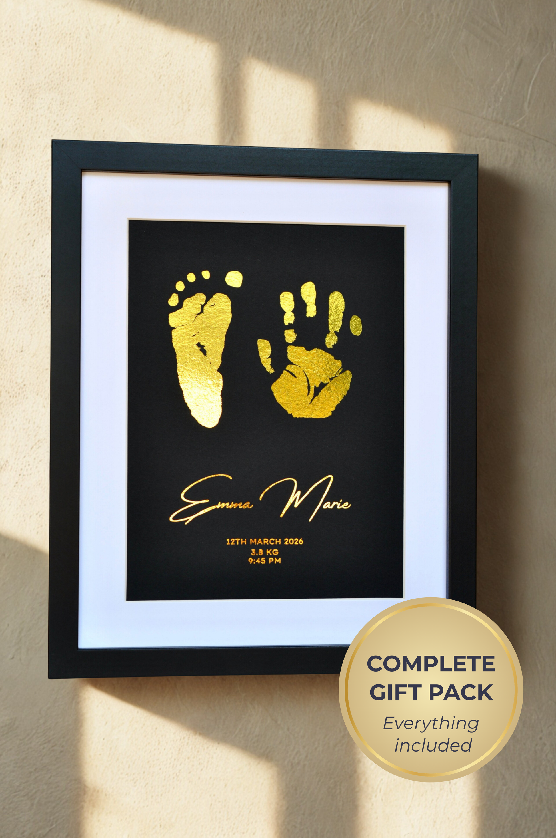 Framed artwork with gold hand and footprints and text on a beige wall.