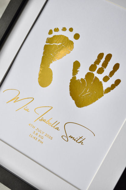 Framed gold hand and footprints with baby's name and birth details on a white background