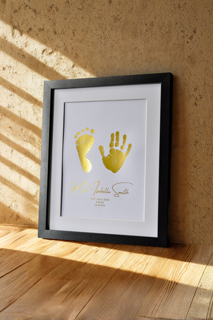 Framed print with gold hand and footprints on a textured wall.