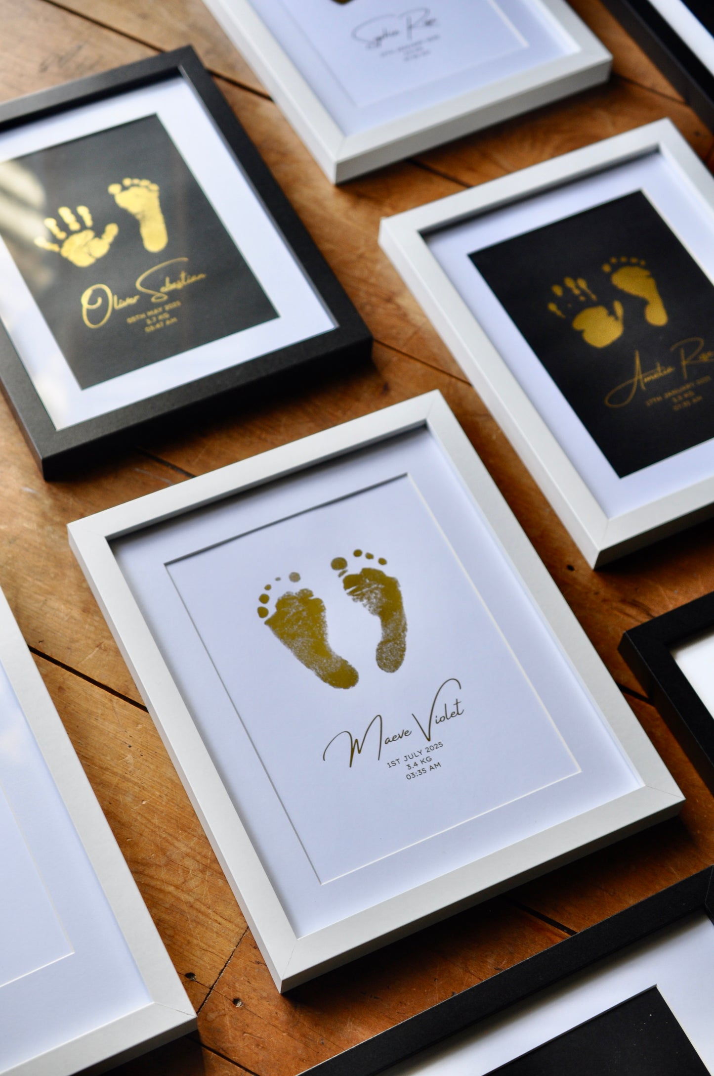 Framed keepsakes of footprints with names on a wooden surface