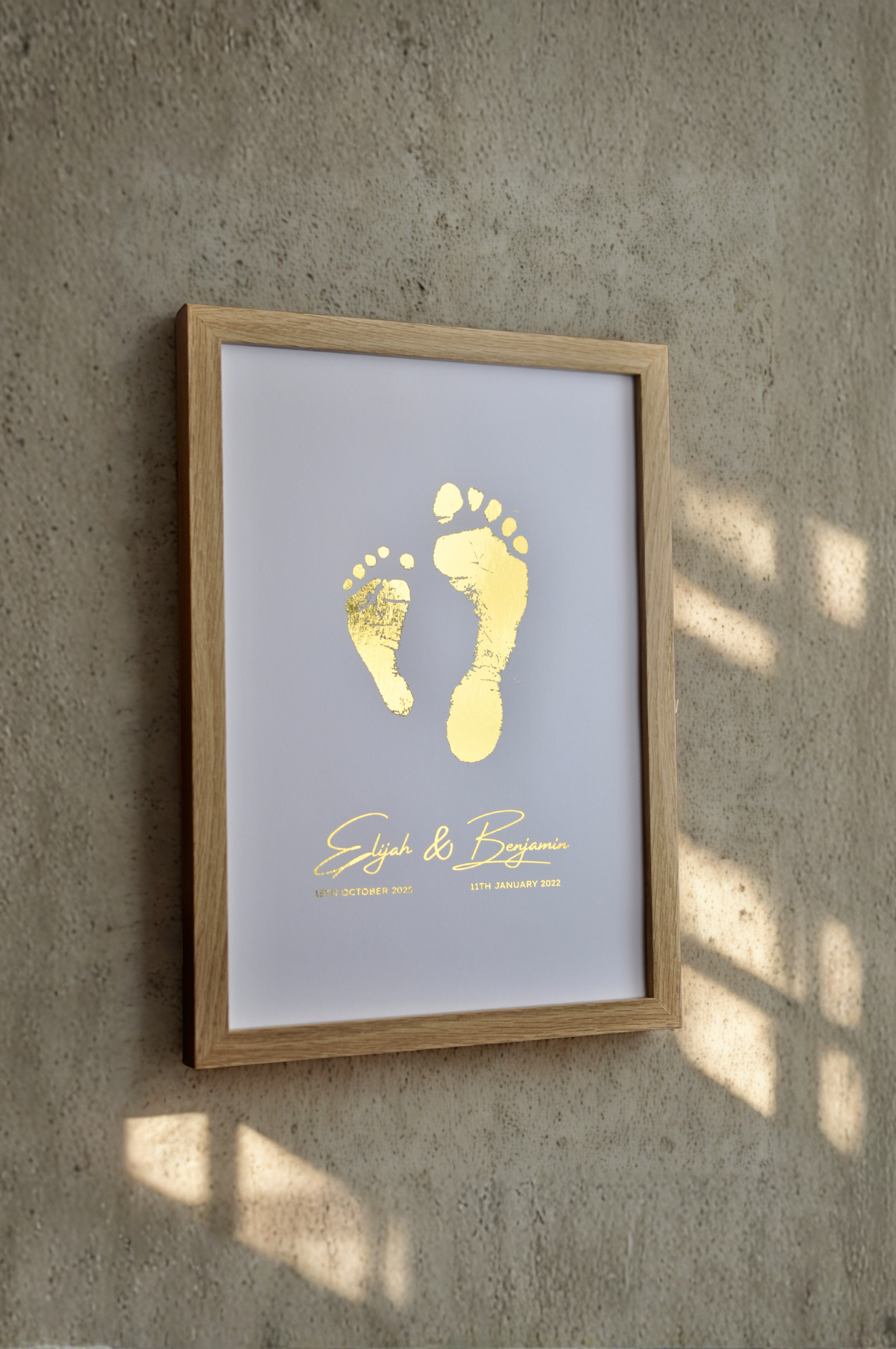 Framed artwork with gold footprints and text on a gray wall