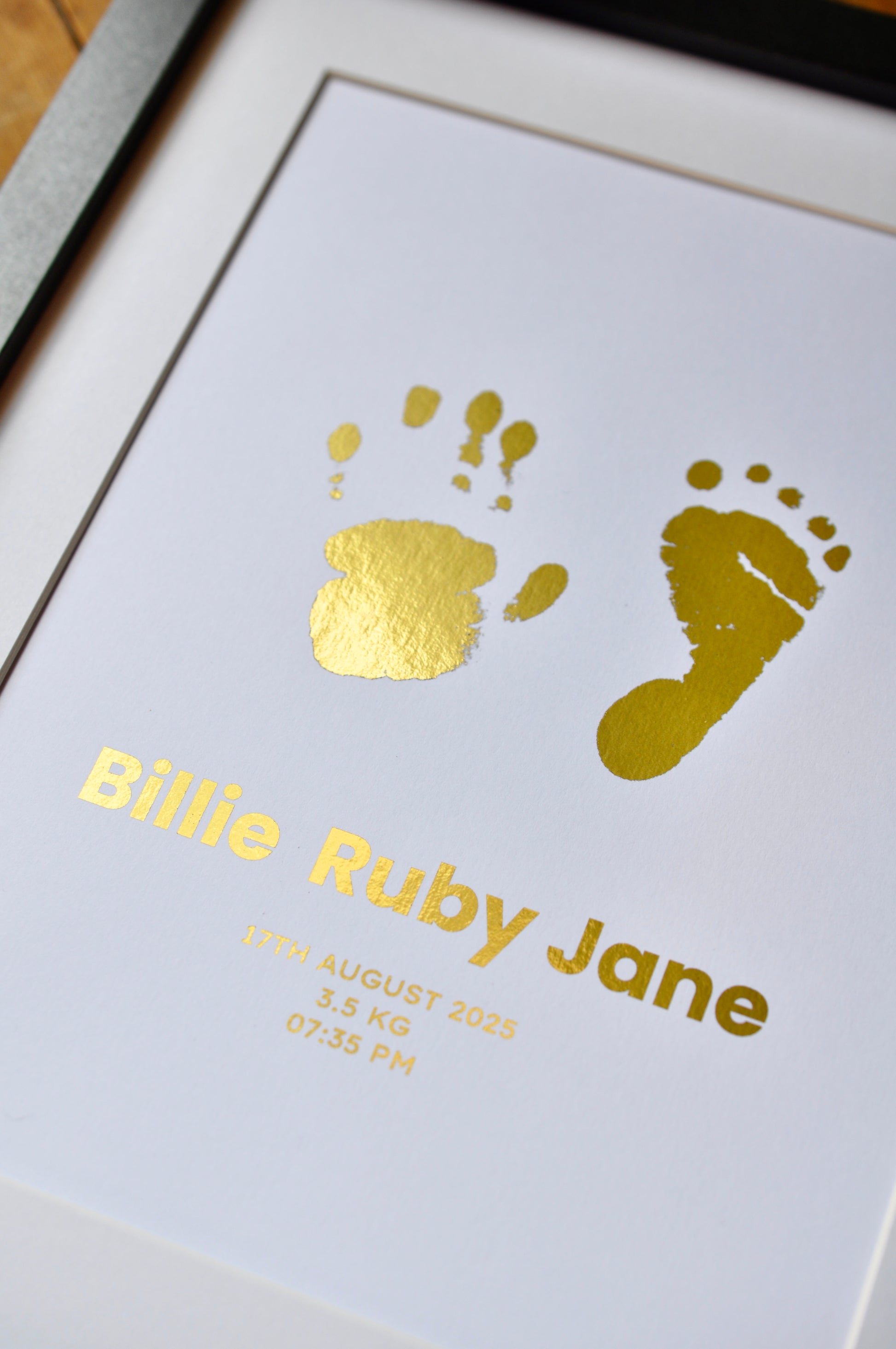 Framed print with gold baby footprints and name 'Billie Ruby Jane' on a white background