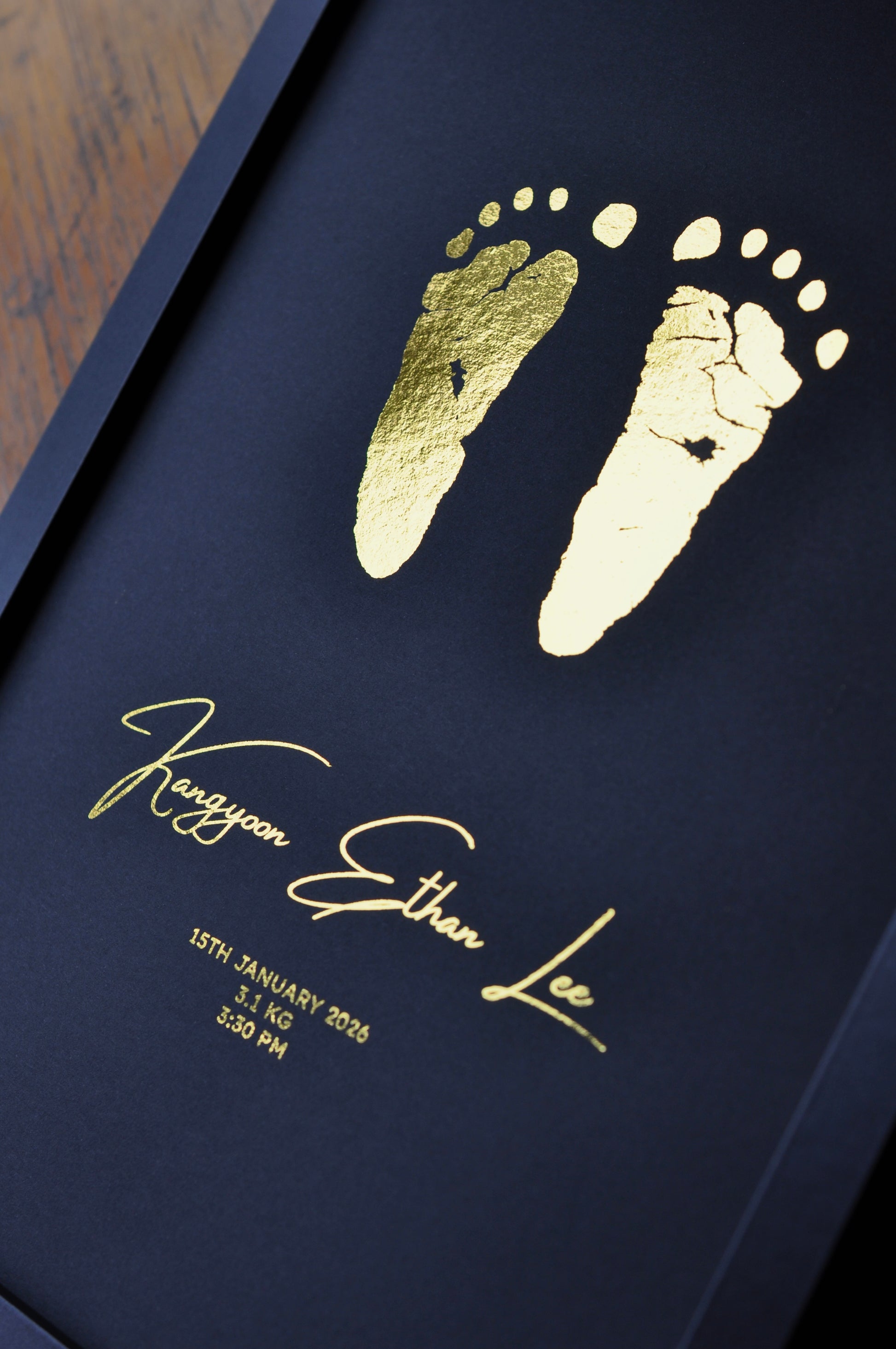black background with gold foil baby footprints and name with birth details