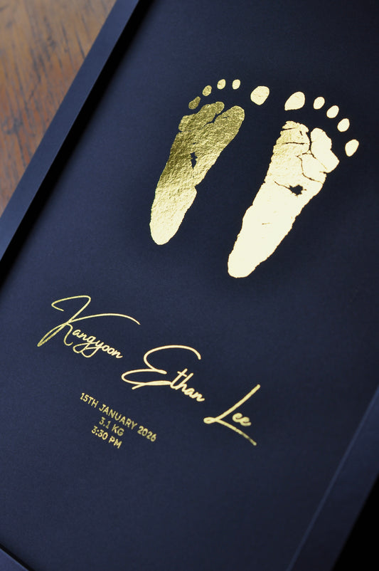 black background with gold foil baby footprints and name with birth details