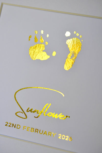 Gold foil baby footprints and handprints on a white card with 'Sunflower' and date printed.
