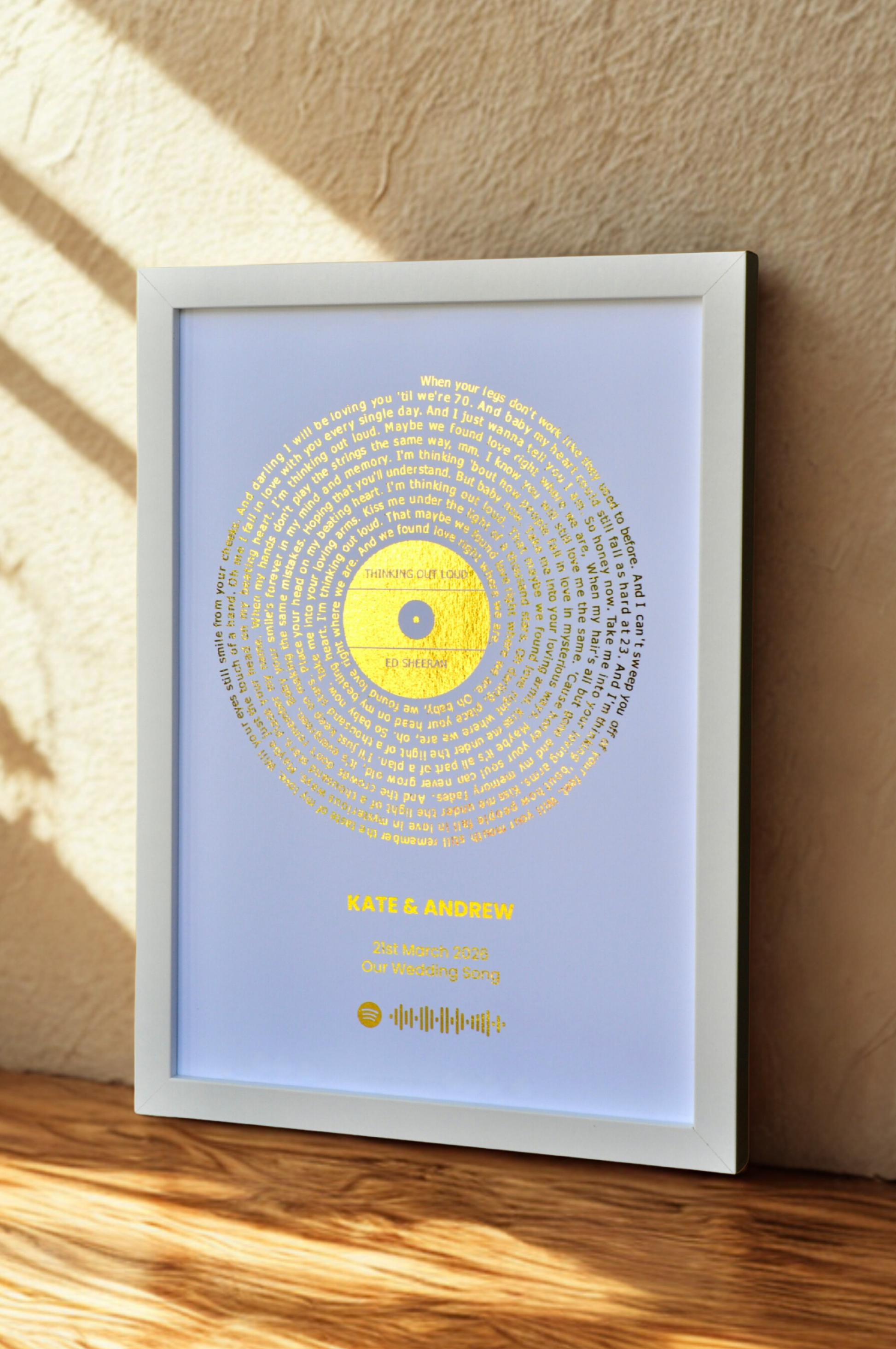 Framed artwork with a white background and golden circular design on a wooden surface.