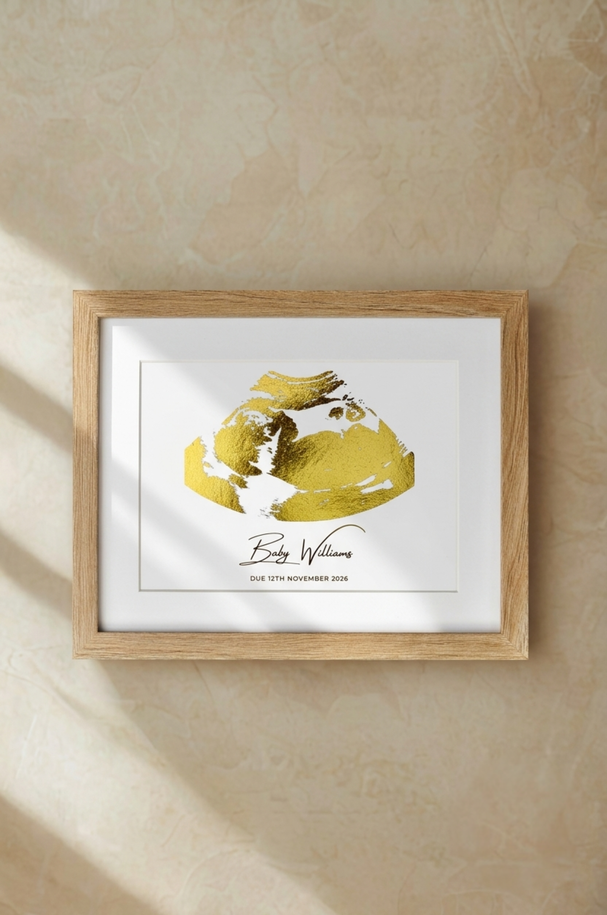 Framed ultrasound in gold foil on a beige wall