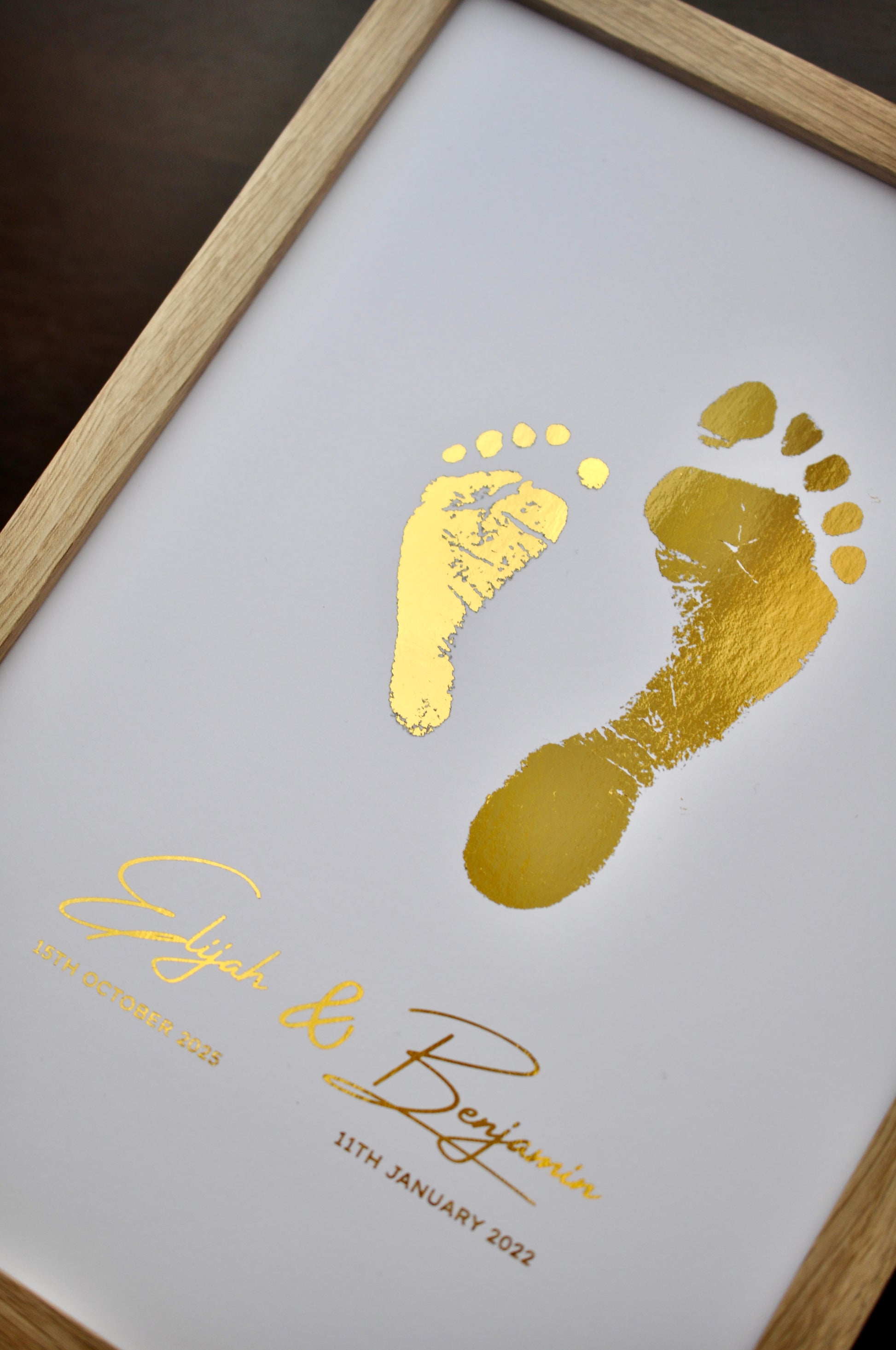 Framed artwork with gold footprints and personalized text on a white background