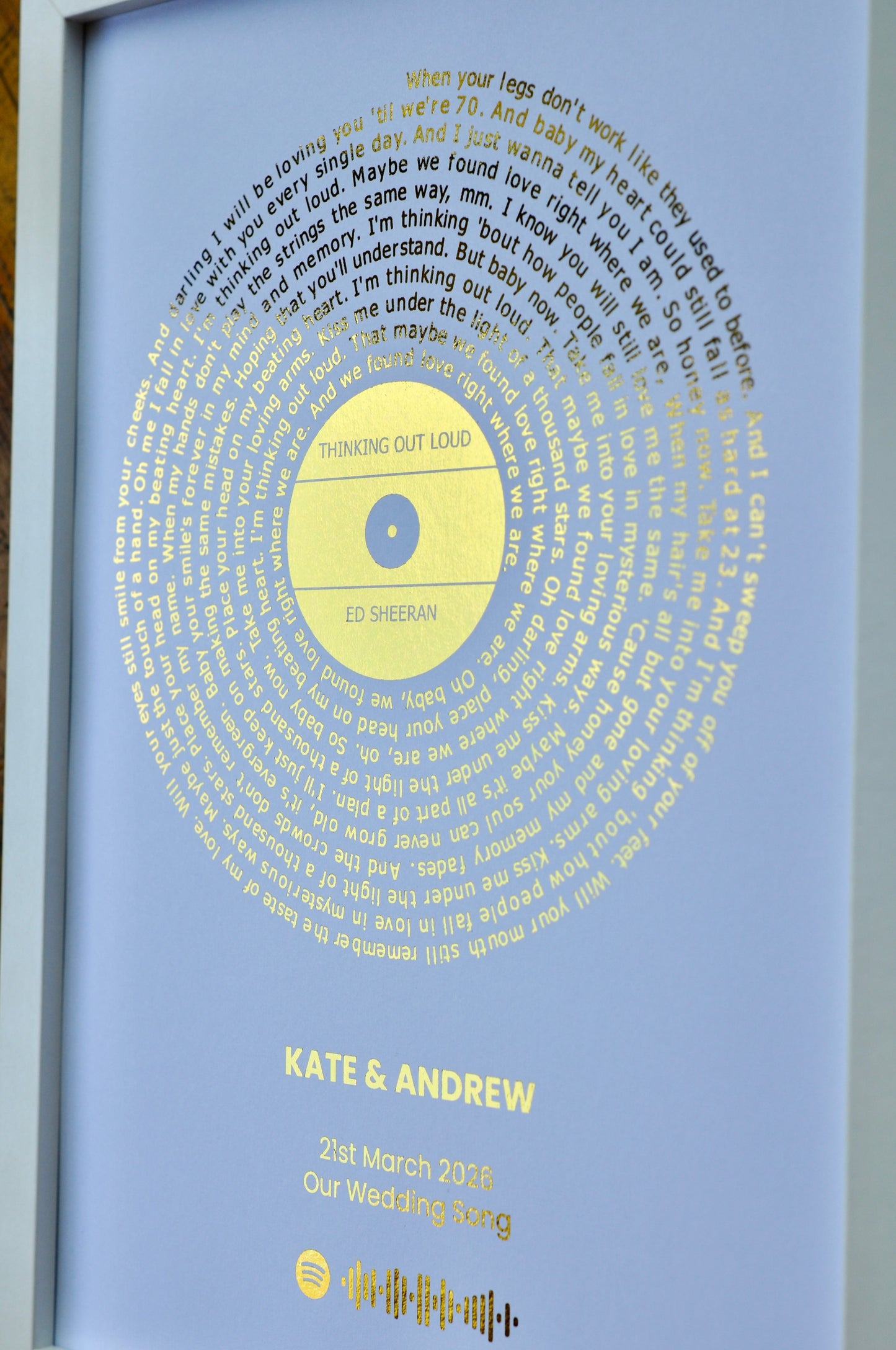Personalized framed artwork with text and a golden song lyrics circle, featuring 'Kate & Andrew' and a date.